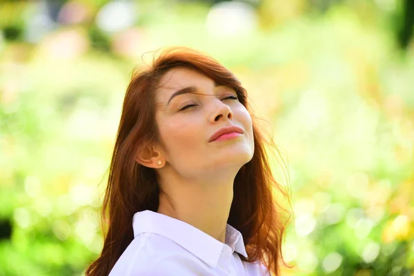 Close up portrait of a sensual young woman with red hair and natural makeup. Beautiful happy young woman enjoying smell in flowering spring garden. — Stock Photo, Image