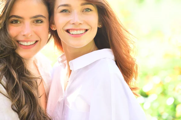 Två kvinnor vänner skrattar med en perfekt vita tänder med en grön vår bakgrund. — Stockfoto