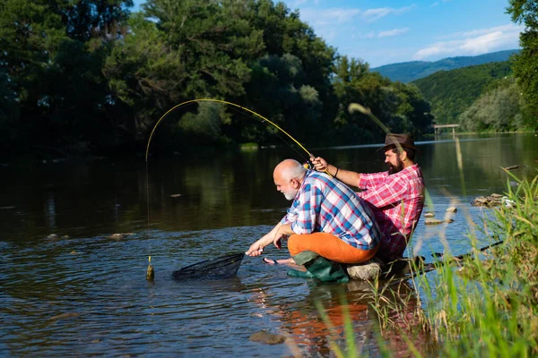 Uomini pesca rilassante mentre godendo hobby. Pesca d'acqua dolce lago stagno fiume. Pescatori con i cappelli. Due amici maschi che pescano insieme. Un hobby maschile. Sono in pensione. Attività e hobby . — Foto Stock