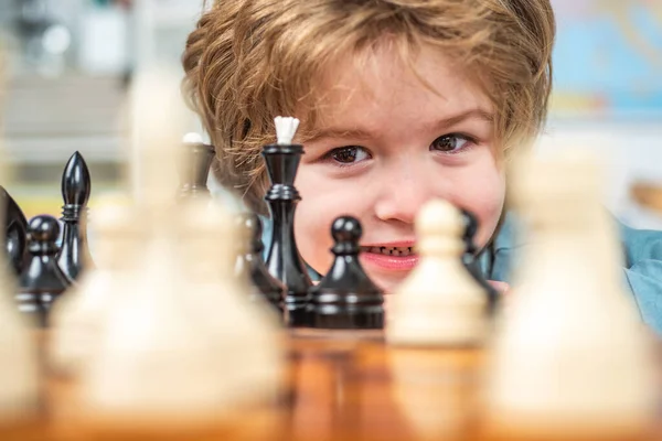 Little clever boy thinking about chess. Intelligent, smart ass kids. Games good for brain intelligence concept. Partrait close up, funny face.