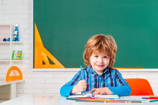 Portret ucznia szkoły podstawowej w pomieszczeniach. Uczeń uczy się liter i cyfr. słodkie mały przedszkolak chłopiec z nauczyciel badania w a klasa. — Zdjęcie stockowe