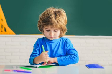 Çocuk eğitimi. Okul çocukları. Okuldan sonra. Öğrenme ve eğitim kavramı. Ev ödevi. Sınıfta tahtaya yakın sevimli bir çocuk var..