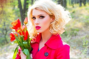 Bahar çiçekleri açan bir kadın. Çiçekli kırmızı elbiseli güzel kız. Çiçekli laleler, bahar çiçekli arka planda..