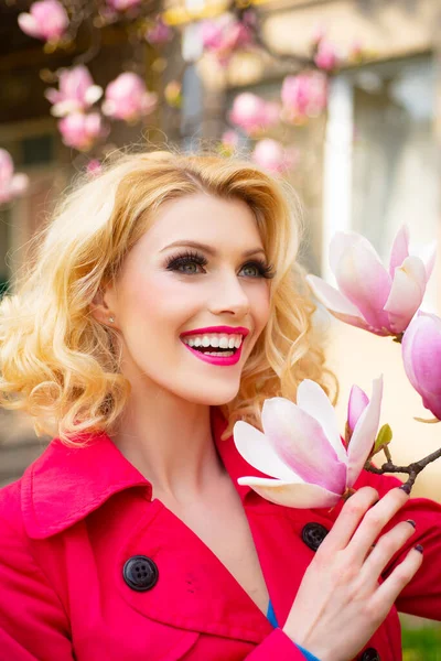 Portrait of a beautiful young girl holding magnolia flower. Spring make-up. — Stock fotografie