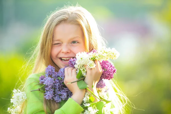 Tiener meisje met boeket van paars en wit lila knipperen. Grappig lachende tiener meisje met lente bloemen. — Stockfoto