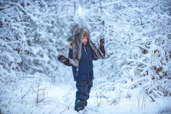 Utomhus porträtt av söt liten unge i kallt soligt vinterväder i parken. Liten tomte går på vintern på snötäckta fält. — Stockfoto