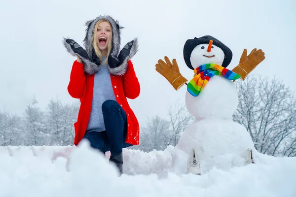 Femme d'hiver. Joyeux hiver fille faisant bonhomme de neige. Noël excité les gens en plein air. Enfant heureux jouant avec un bonhomme de neige lors d'une promenade hivernale enneigée . — Photo