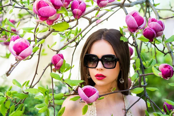 Retrato de modelo de belleza con gafas de sol. Primavera moda modelo mujer posando sobre Magnolia flores fondo . — Foto de Stock