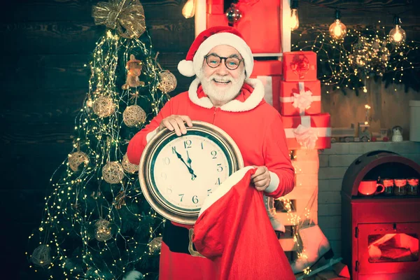 Erntedankfest und Weihnachten. Weihnachtszeit. Grußkarte Weihnachten. Der Weihnachtsmann zu Hause. Der Weihnachtsmann schaut auf seine Uhr. — Stockfoto