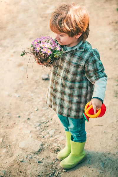 Glücklicher kleiner Bauer, der Spaß auf dem Feld hat. Kleinkinder arbeiten im Blumenpark. Gartenarbeit mit einem Kind. Kinderporträt auf Ackerland. — Stockfoto