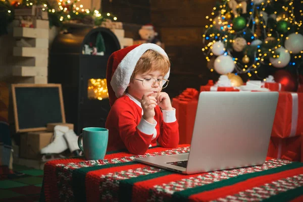 Compras on-line de Natal para crianças. Criança tipo carta ao Pai Natal. Ajudante de Santa usando notebook . — Fotografia de Stock