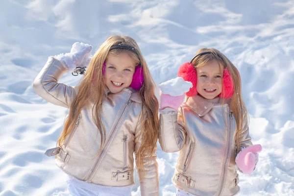 Söta systrar som leker i snö. Vinterbarnporträtt. Porträtt av två små flickor leker med snö på vintern. — Stockfoto