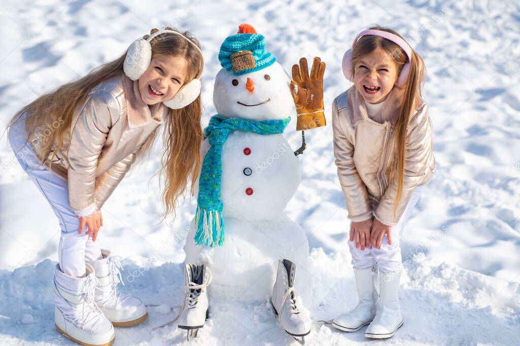 Kids make Snowman on white snow background. Making snowman and winter fun for children.