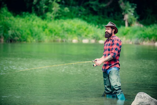 Hombre guapo relajándose. Fines de semana o vacaciones de verano. Unidos con la naturaleza. Pesca en el lago. Fin de semana. Pasatiempo peces mosca de los hombres en camisa a cuadros. Pothunter. Descanso y recreación . — Foto de Stock