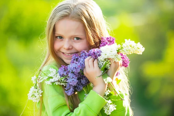 一个少女带着一束紫丁香有趣的少女在户外玩得很开心。春花. — 图库照片