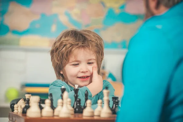 Thuis. Educatieve spelletjes. kleuter of schooljongen, vrolijke glimlachende kleine jongen zitten aan de tafel en evincing blijdschap tijdens het schaken. — Stockfoto