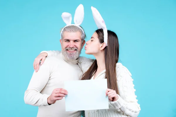 Glad påsk par kyssas, kanin kanin kvinna och man hålla ombord papper för text kopiera utrymme. Rolig påsk kanin par på blå bakgrund isolerad. — Stockfoto