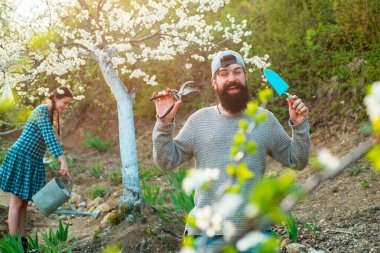 Aletleri olan bahçıvan. Çiçek bahçesinin yanındaki bahçede çalışan çiftçi. Bahçıvan bahçede bahçe aletleriyle çalışır ve iyi vakit geçirir..