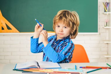 İlkokuldan komik bir çocuk. Okul çocukları yeşil karatahtaya karşı. Çocuk okula hazırlanıyor..