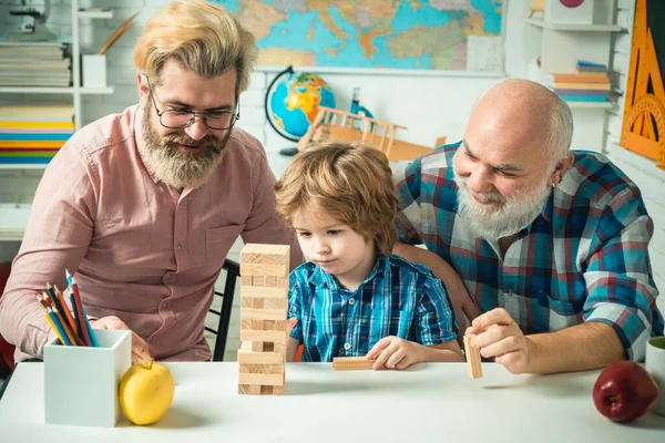 Dědeček učí vnuka hrát hry Jenga. Mužský vícegenerační portrét. — Stock fotografie