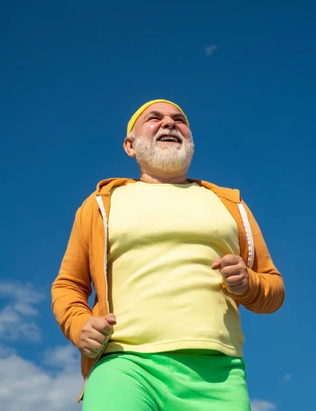 Concetto di pensione. Muoviti. Un uomo anziano che fa jogging nel parco. Un concetto di stile di vita sano. Corridore anziano in natura. Vacanze estive e attive . — Foto Stock