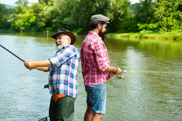 Father and adult son fishing in lake. Family time. Man bearded fisher. Fishing team. Big game fishing. Retired bearded fisher. Keep calm and fish on. I am happiest man. Friends fishing.