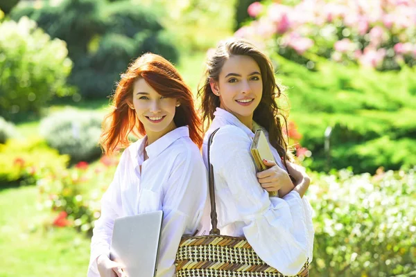 Studenten meisjes. Twee studenten staan in het zomerpark. Twee vrouwelijke studenten praten en lachen na de lezing. — Stockfoto