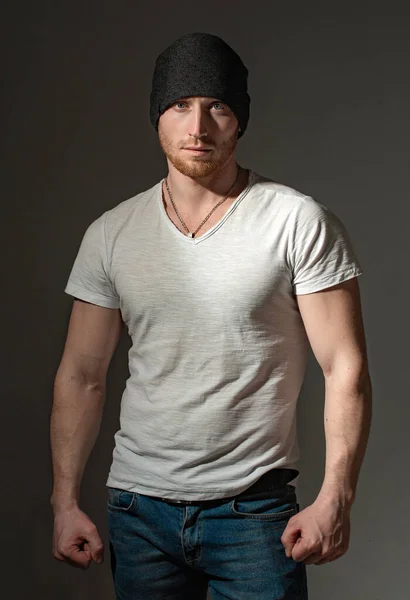 Man style and fashion. Brutal masculine man close up studio portrait. Handsome man with ginger red hair. Sexy ginger unshaven brutal man wearing beanie cap and white t-shirt.