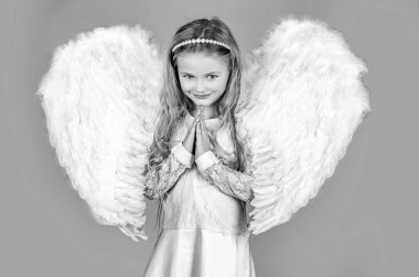Melek yüzlü çocuk. Melek kanatlarıyla poz veren tatlı bir kız çocuğu. Kollarını göğsüne yaklaştırıp dua eden güzel bir melek kız. Meleklerin küçük elleri senin için çapraz.