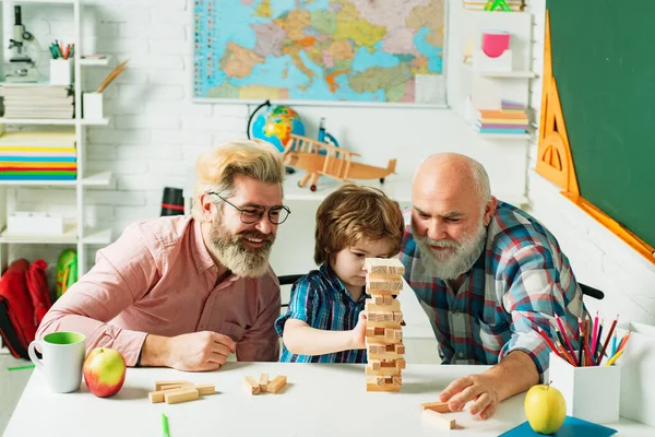 Pupil with father and grandfather enjoying together at home. Happy man family have fun together. Man in different ages. Jenga games for family.