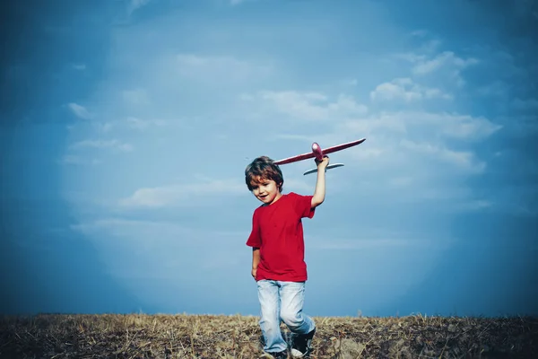 おもちゃの飛行機で遊んでいる子供の男の子と夢の未来。積極的な子供の概念。概念的な子供と自然。幸せな男の子は屋外で飛行機で遊ぶ. — ストック写真