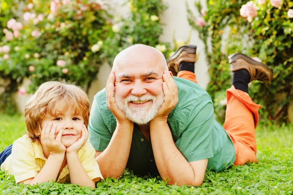 Happy child with Grandfather playing outdoors. Grandfather with Son and Grandson having Fun in Park. Happy grandfather and grandson relaxing together. Grandfather and son.