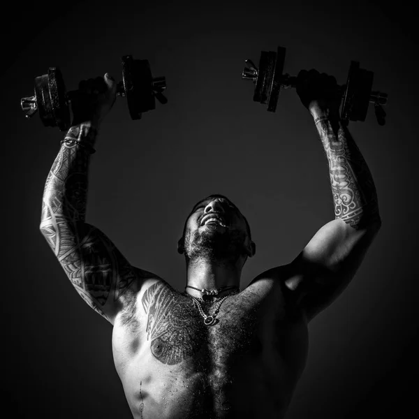 Sterke man die de halters omhoog heft. Intense training. Lichaam met tattoo. — Stockfoto