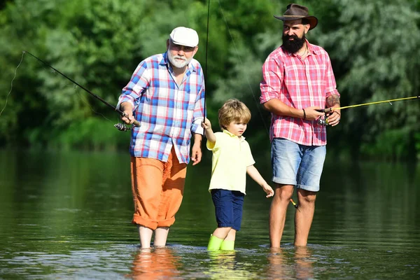 Рыбалка. Летние выходные. Отец и сын рыбачат. Рыбалка в реке. Три поколения: дедушка, отец и сын-подросток. С Днем отца! . — стоковое фото
