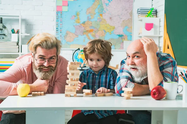 Padre e figlio giocano a Jenga con il nipote. Uomo anziano giocare suo nipote e figlio . — Foto Stock