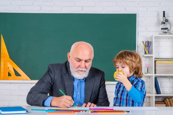 Szkoła podstawowa. Uczniowie uczą się w szkole ze starym nauczycielem. Profesor i uczeń w klasie w szkole podstawowej. — Zdjęcie stockowe