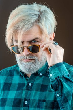 Yakışıklı erkek model, sakallı bıyıklı ve sarı saçlı rahat gömlek giyiyor. Gri arka planda mutlu bir adamın portresi.