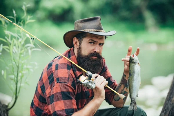 Portret van een man op vakantie. Visachtergrond. Vlieg vissen avonturen. Man gekleed in shirt vissen met staaf op het meer. Weekend tijd. Man visser vangt een vis. — Stockfoto