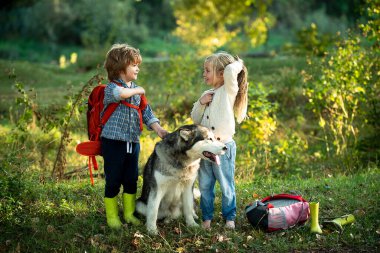 İki çocuk, köpek evcil hayvanıyla birlikte doğa yürüyüşü yapıyor. Kırsal kesimde yaz. Yaz tatili.
