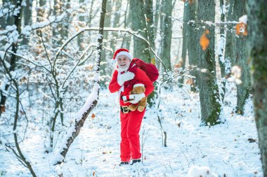 Kırmızı şapkalı gerçek Noel Baba büyük kırmızı hediye torbasını çekiyor. Yeni yıl konsepti. Mutlu yıllar. Mutlu Noeller dilerim..