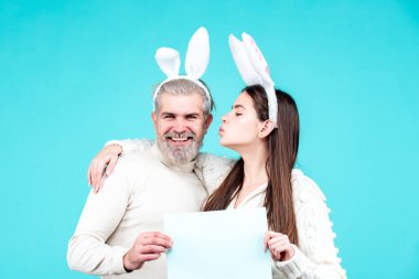 Paskalya tavşanı çifti yazı için tahta kağıdı tutuyor. Mavi arka planda paskalya tavşanı kostümlü aile çifti izole edildi. Paskalyayı kutlayan tavşan çift.