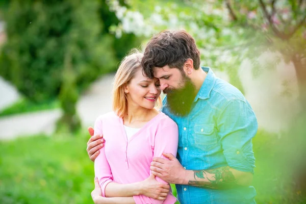 在一个阳光灿烂的日子里,一对快乐的夫妇在春天的公园里微笑.幸福的年轻夫妇在花树附近.年轻貌美的情侣等着接吻. — 图库照片
