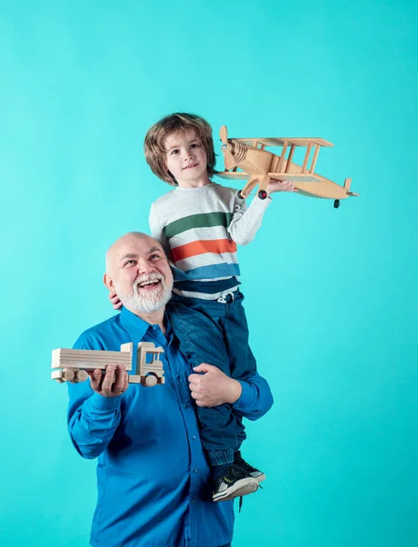 Retrato abuelo y nieto jugando con los juguetes de avión. Relaciones familiares Abuelo y nieto. Concepto de familia masculina. Positivo chico, abuelo y nieto aislado sobre fondo azul . —  Fotos de Stock
