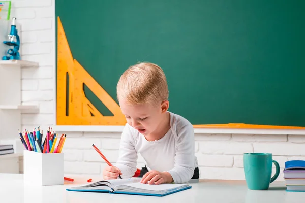 Söt pojke i klassrummet nära skrivbordet. Utbildningsprocess. Små barn på skollektionen. — Stockfoto