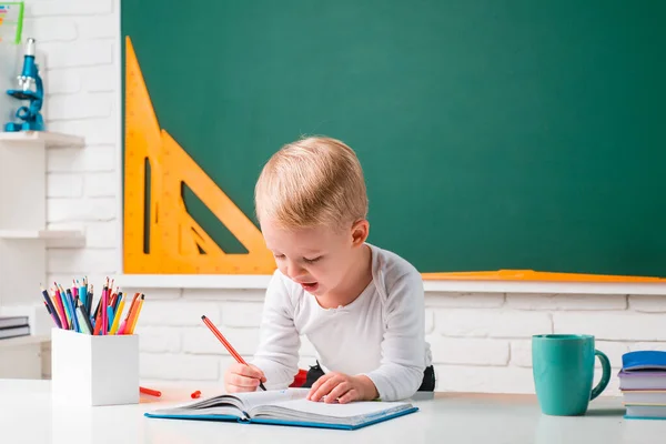 Leuke jongen in de klas bij schoolbord bureau. Educatief proces. Kleine kinderen op school. — Stockfoto