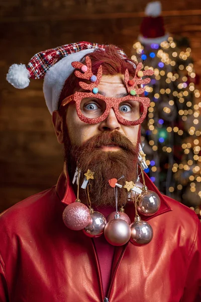 Мужчины в зимней одежде. Новогодняя рождественская идея. Санта-Клаус в шляпе держит рождественский подарок. Счастливый Санта одет в зимнюю одежду думать о Рождестве возле елки . — стоковое фото