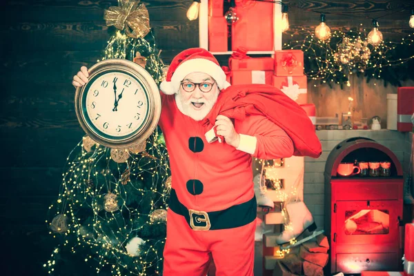 Foto des Weihnachtsmannes mit einer Uhr, die fünf Minuten vor Mitternacht zeigt. Frohes neues Jahr. Der Weihnachtsmann mit echtem Bart hält die Uhr. Weihnachtsmann mit Wecker. — Stockfoto