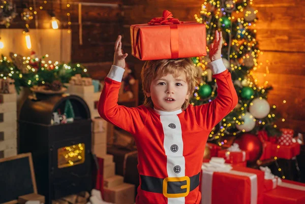 クリスマスの子供は頭の上に箱がある。クリスマスプレゼント付きの幸せな子供。新年のクリスマスの概念。ホームクリスマスの雰囲気. — ストック写真