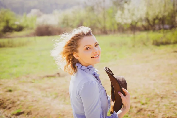 Piękna młoda kobieta na wiosennym tle ogrodu patrząca w kamerę. Kobieta rolnik na ziemi uprawnej. Stań się rolnikiem ekologicznym. — Zdjęcie stockowe