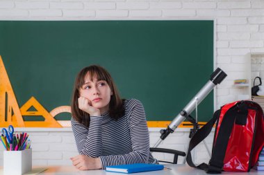 Okuldan sonra. Mutlu genç kız içeride bir masada oturuyor. Bireysel öğretim. Okul çağındaki genç bir kızın portresi. Kapalı alanda çalışıyor..